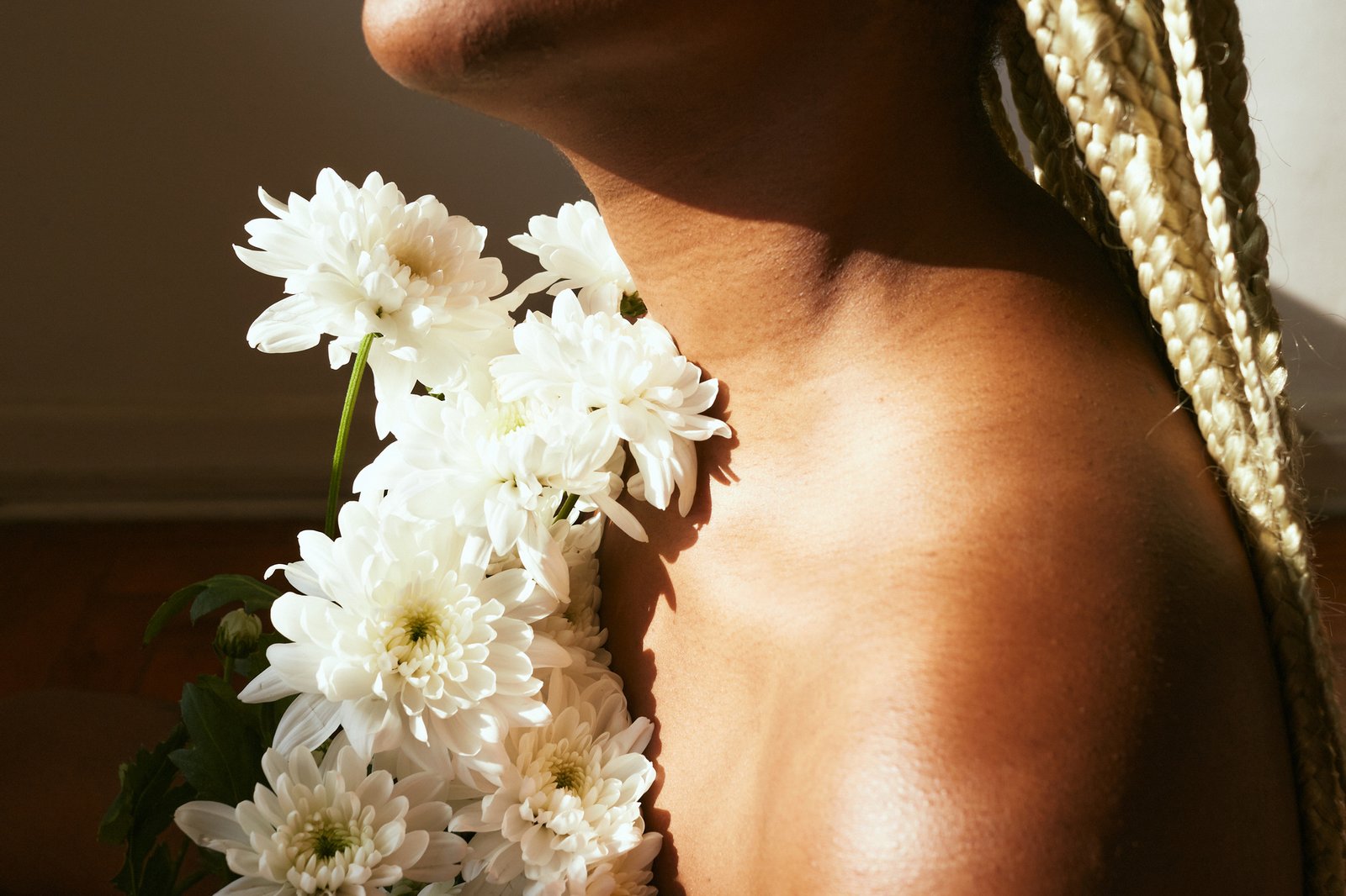 White flowers resting against a shoulder in warm light